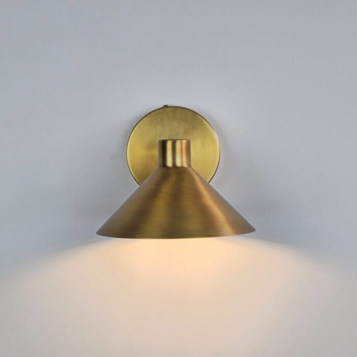 Luxury Wall Sconce Light, Modern cone-shaped brass wall sconce emitting a warm downward glow against a white wall.
