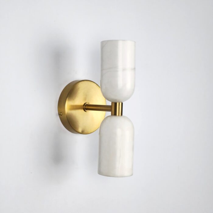 Alabaster stone wall light featuring a modern, handcrafted design with dual cylindrical shades and a brushed raw brass mount, ideal for luxury bedside or living room decor.