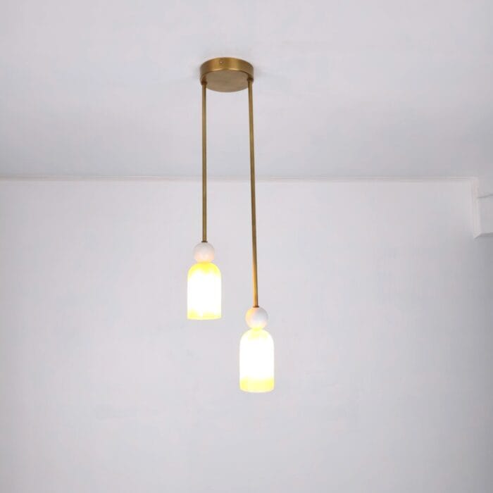 Luxury Alabaster pendant light fixture featuring two cylindrical alabaster stone shades with natural yellow-white marbling, suspended from a circular brass ceiling plate by slender brass rods,